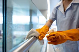 Close-up on a cleaner working at a hospital and cleaning a handrail - janitorial service concepts