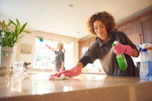 two professional cleaners in a domestic kitchen spraying cleaner onto a granite work surface .